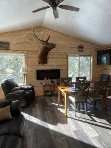 A living room with a lot of furniture and a deer head on the wall.