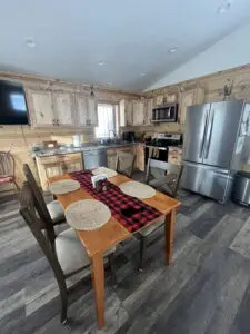 A kitchen with a table and chairs, refrigerator, microwave, oven, and dishwasher.