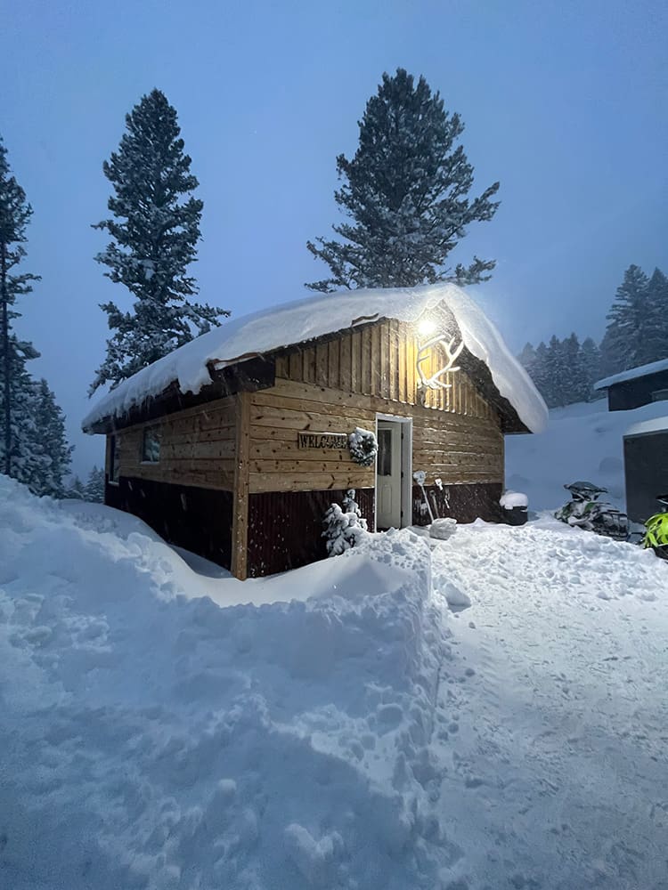 A cabin is covered in snow and has lights on the roof.
