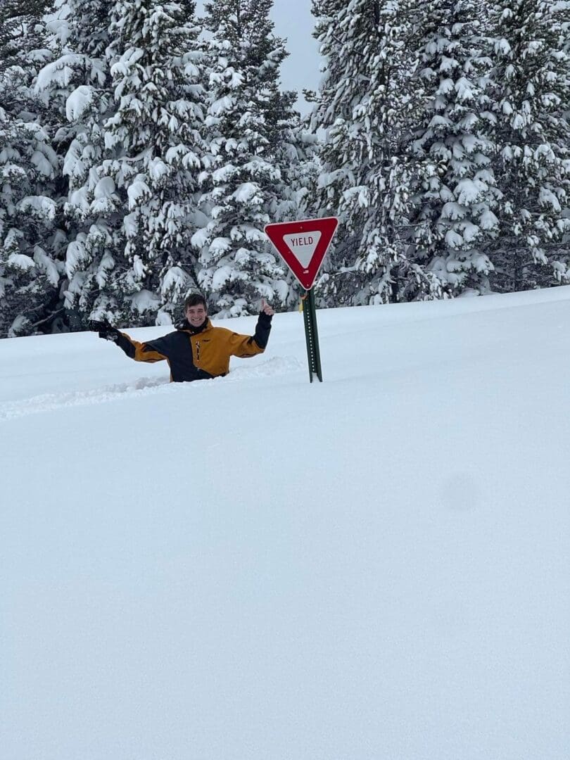 A person is laying in the snow near a sign.